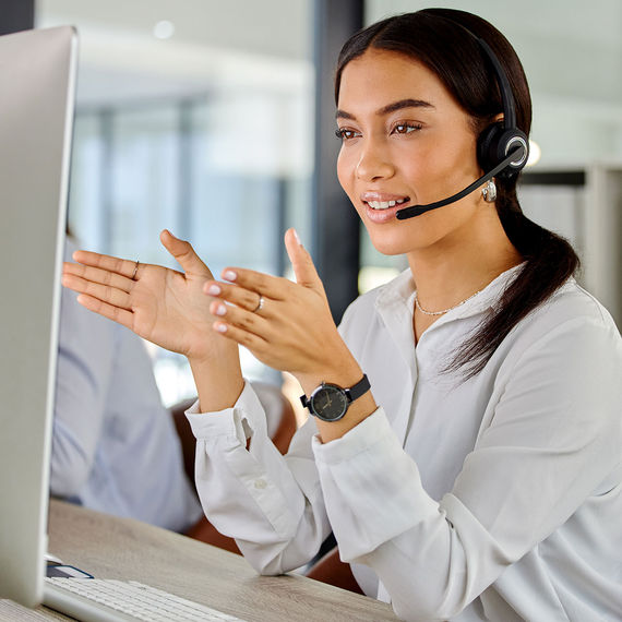 Lachende vrouw met draadloze headset in een modern kantoor tijdens een gesprek.